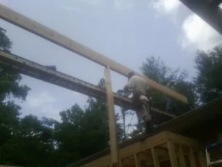 Carpenter setting a ridge beam over a new addition frame — Ice Dam Removal by Roofing Brothers in Swayzee