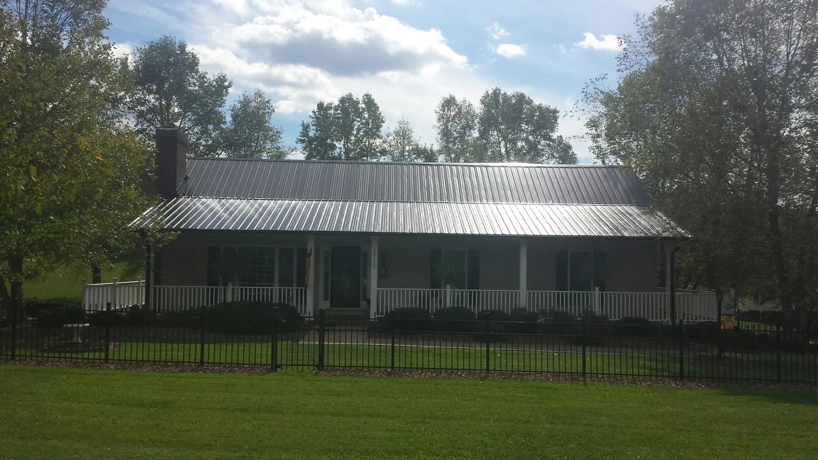 Gray metal roof on a brick ranch with a full width front porch — Gutter Guard Installation work by our crew in Swayzee