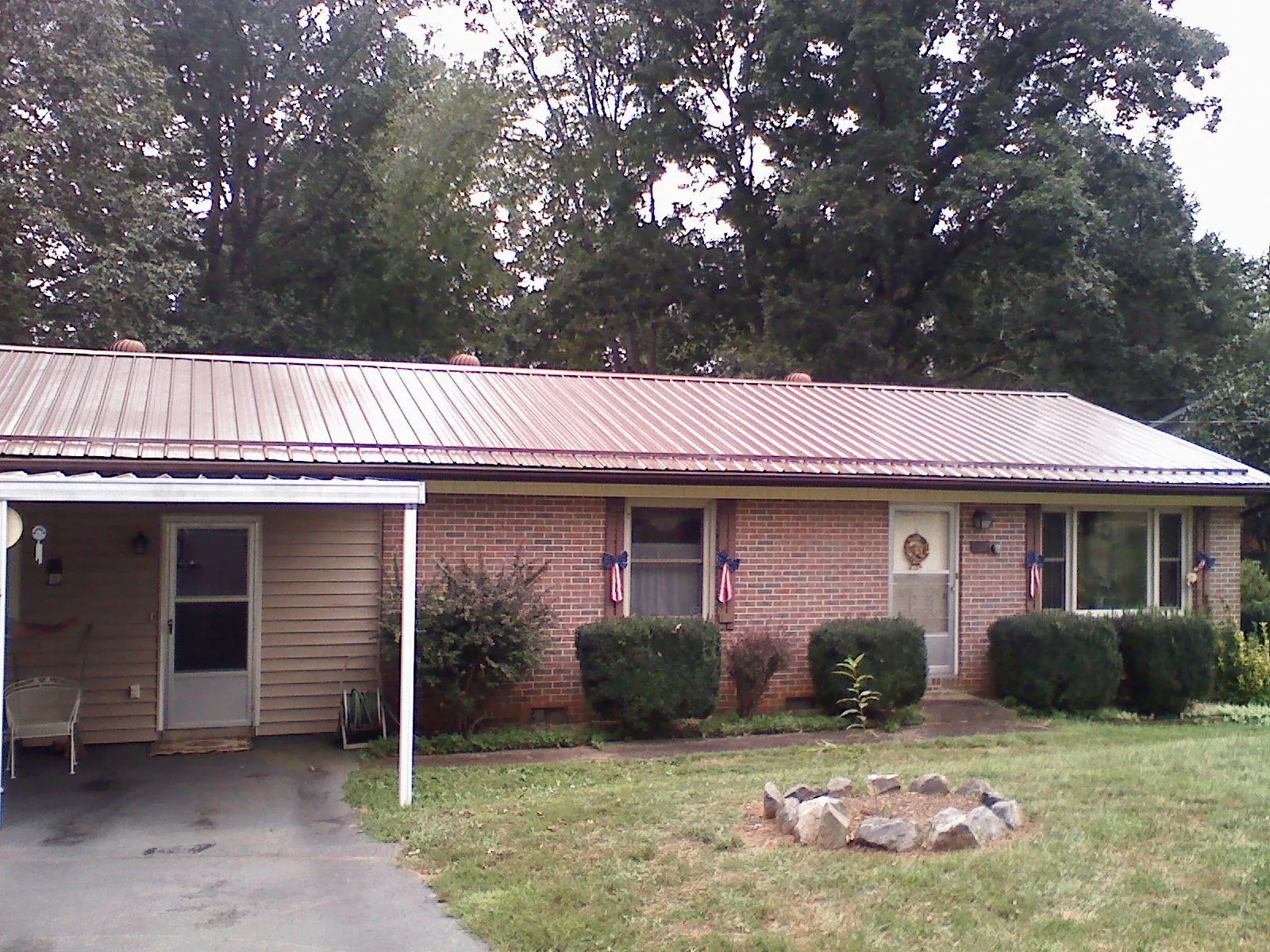 Bronze metal roof and carport on a brick ranch home — Roof Repair work by our crew in Swayzee
