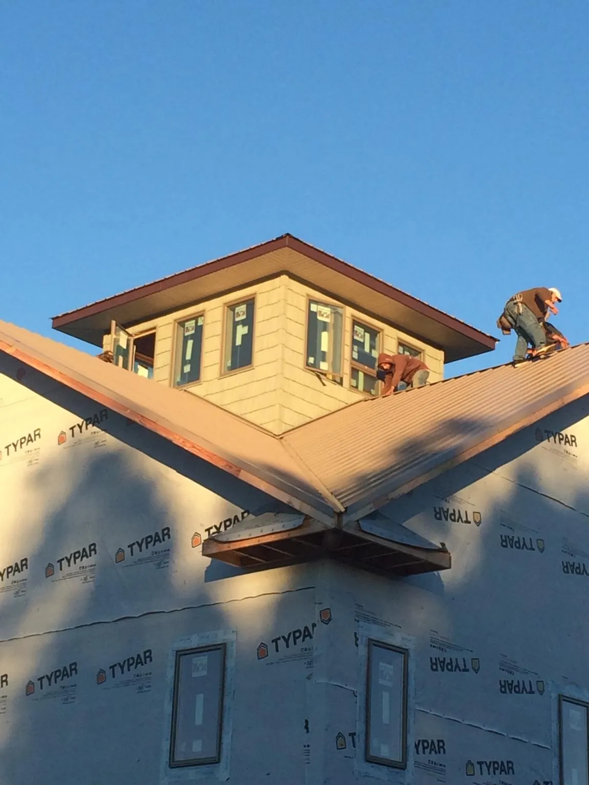 Roofers working around a rooftop cupola on a new metal roof at sunset — Roof Waterproofing in Swayzee by Roofing Brothers